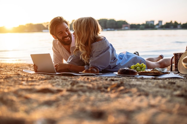 Couple in love on a picnic date using tablet