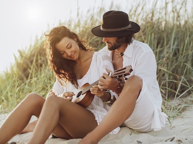 Couple in love playing guitar and resting on the beach