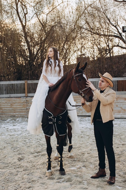 冬の夕暮れ時の牧場で馬に乗って愛のカップル