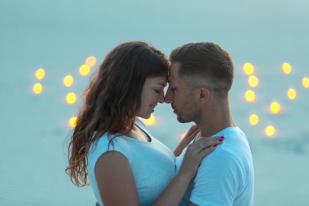 Couple in love romantic hugs in sand desert. Evening, romantic atmosphere, in sand burn candles