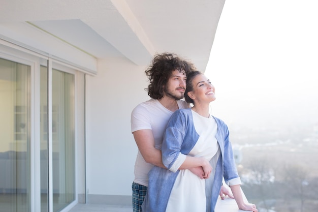 Couple in love sharing emotions and happiness while hugging on the balcony at home