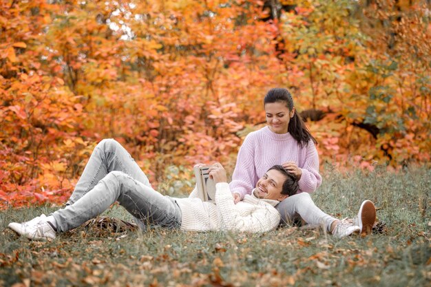 Photo couple in love sitting in autumn park and reading book