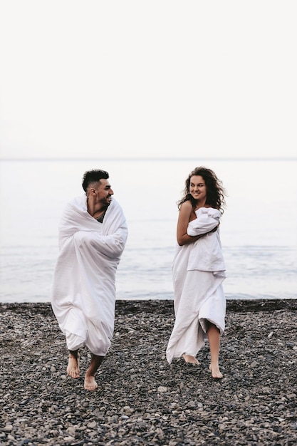 A couple in love spend the night at the sea kissing and hugging on the beach covered with a blanket