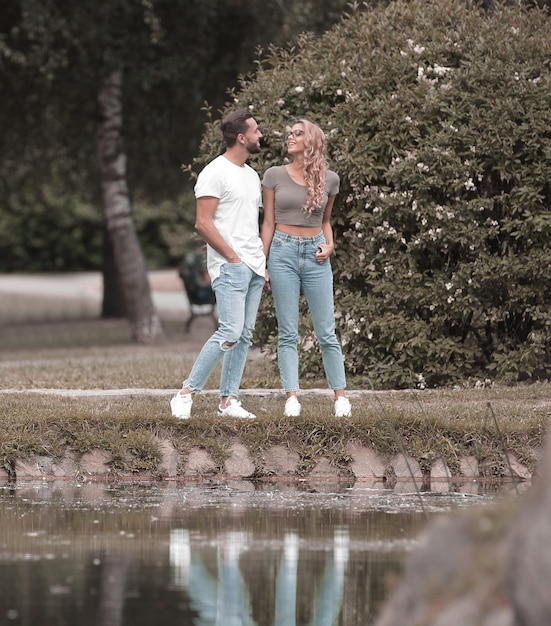 湖の近くの芝生の上に立っている愛のカップル