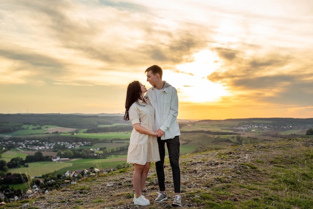 A couple in love stands on a mountain at sunset