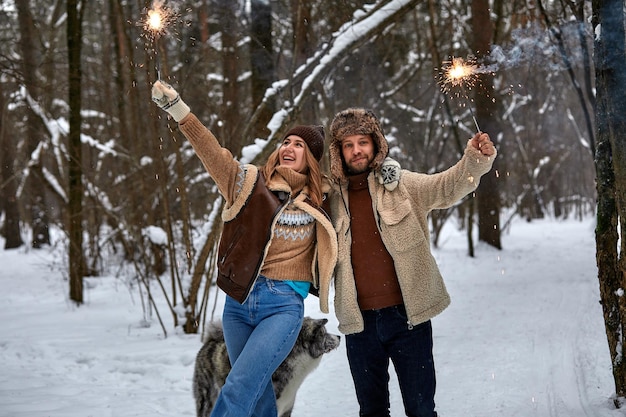 Couple Love Story in Snow Forest Kissing and Holding Sparklers Couple in Winter Nature Couple Celebrating Valentines day date