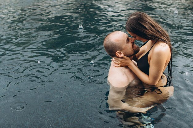 Couple in love swimming together in the sea under the warm summer rain