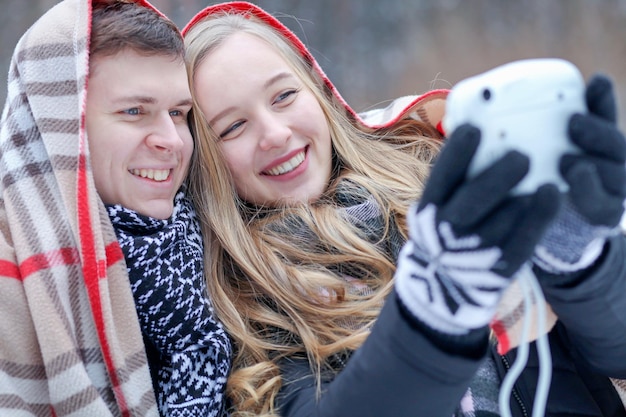 a couple in love takes a selfie on a camera wrapped in a blanket