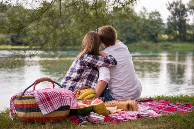 Photo couple in love taking a selfie by mobile phone while enjoying picnic time drink and food in beautiful nature on the river bank