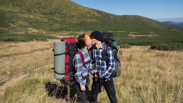 愛の観光客の男性と女性のカップルが情熱的にキスする山の平野に立つ