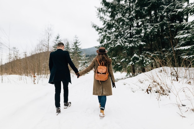 Влюбленная пара гуляет по снегу, вид со спины