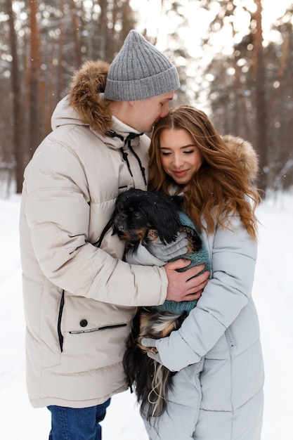 A couple in love walks their dog in the winter forest