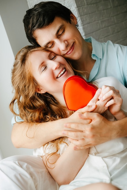 Photo couple in love watches a gift heart box on valentine's day holiday.