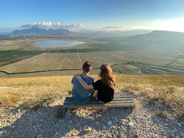 恋するカップルが美しい山の風景に沈む夕日を一緒に眺める