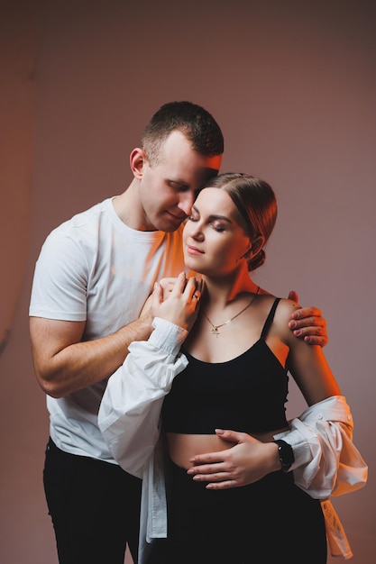 A couple in love in white shirts are hugging and enjoying each other A stylish couple embraces each other on a white background Happy family concept