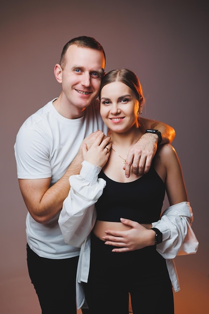 A couple in love in white shirts are hugging and enjoying each other A stylish couple embraces each other on a white background Happy family concept