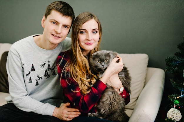 Couple in love, with a cat, posing in couch