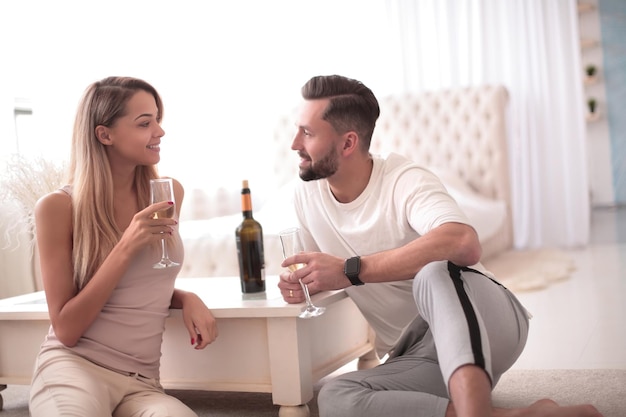 Влюбленная пара с бокалами вина разговаривает, сидя на кухне