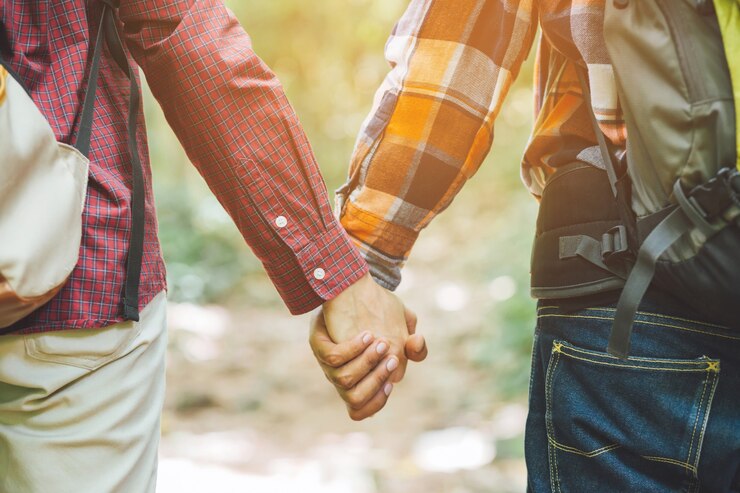 Photo couple lovers holding hands towards the sun with bright sun flare in parks