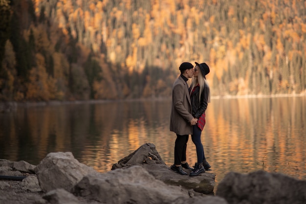 A couple of lovers man and woman stand near the lake between the mountains.