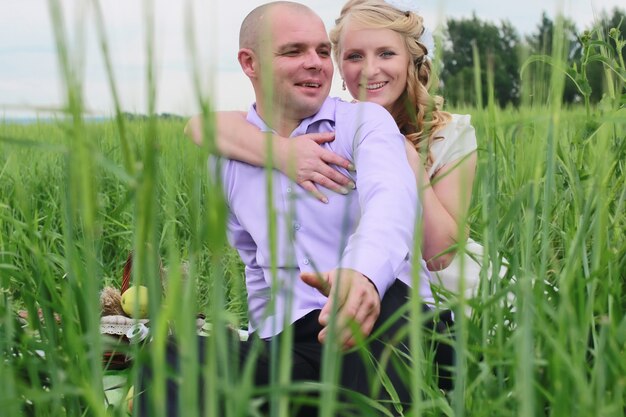 Couple lovers walking in a green field in summer day