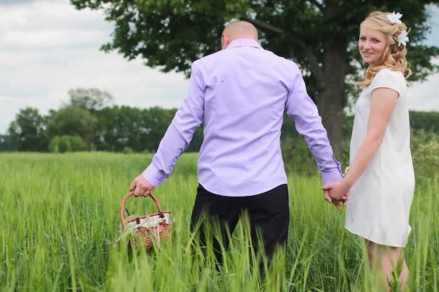 Couple lovers walking in a green field in summer day