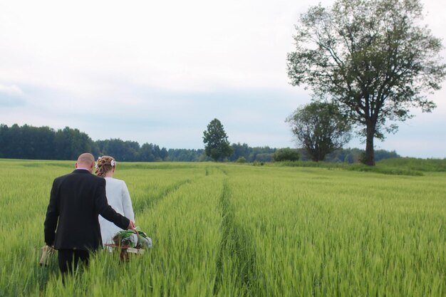 Couple lovers walking in a green field in summer day