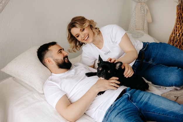 A couple lying on a bed with their dog