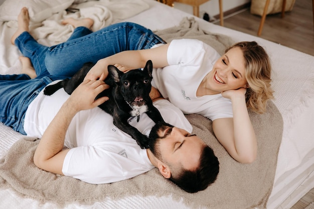 Couple lying on the bed with their dog