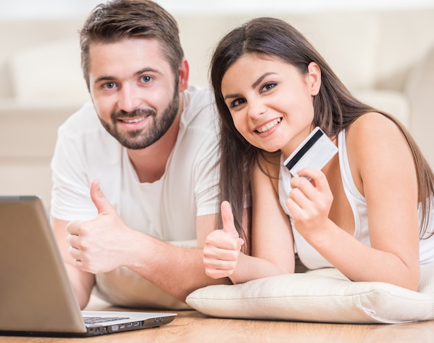 Couple lying on the floor at home and making order online.