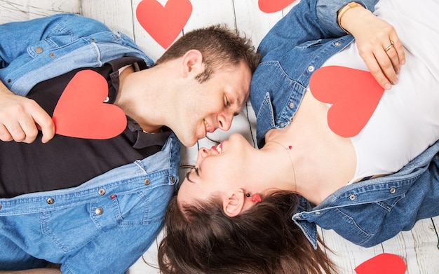 Couple lying on the wooden floor with hearts