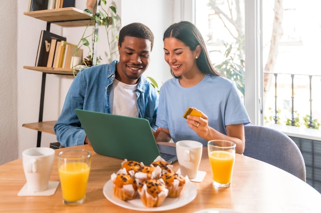 Photo couple making purchase online with the computer while having breakfast next to the window shopping on the internet