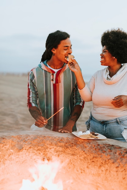 Couple making s'mores at the beach