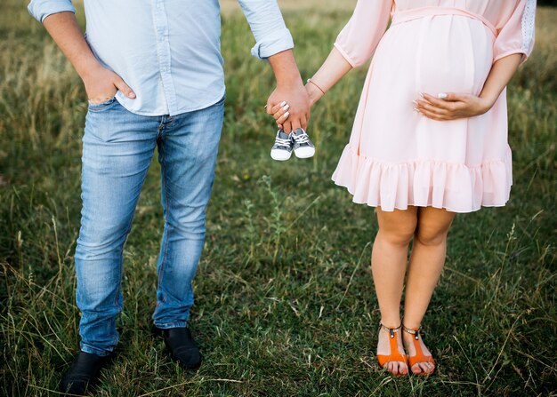 Couple of a man and pregnant woman holding small baby shoes