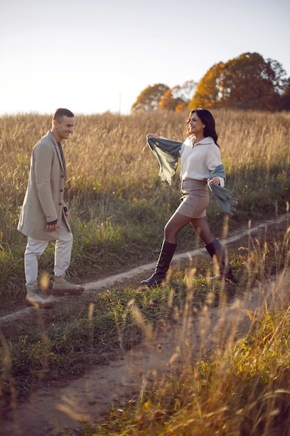 Couple of a man with a woman in a field with dry grass at sunset in autumn