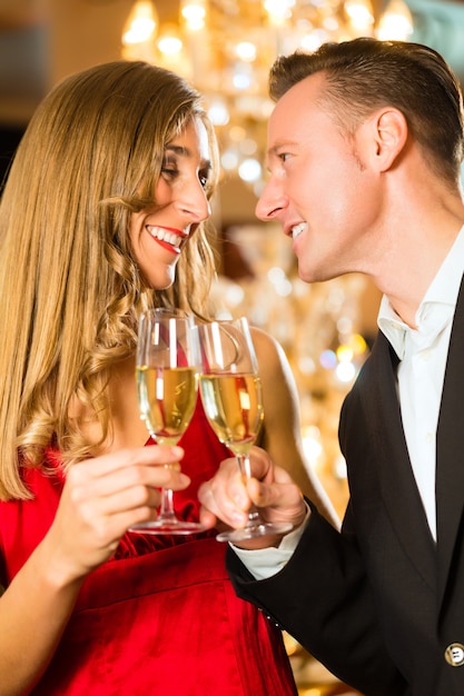 Couple, man and woman, drinking champagne in a fine dining restaurant, each with glass of sparkling wine in hand