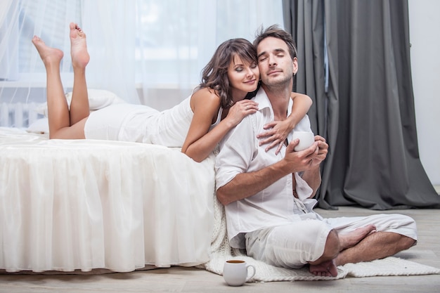 Couple man and woman at home in bed with a Cup of coffee. Love, family, relationships, tenderness