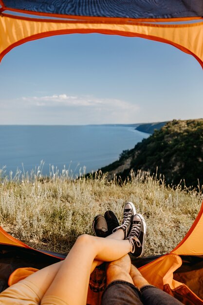 Couple of man and woman sitting in a tent, legs cropped.