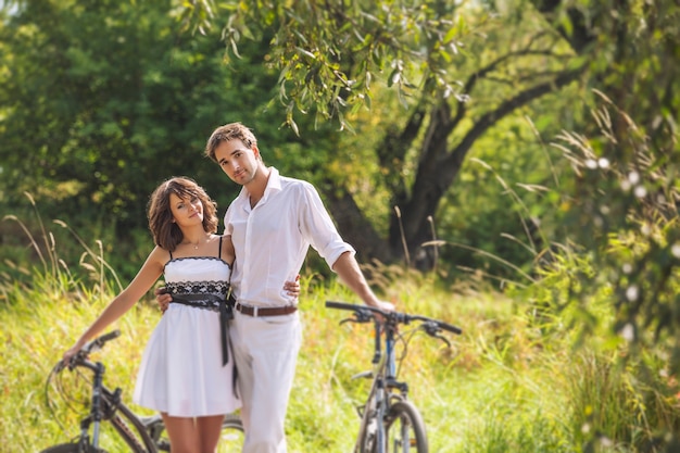 自然の中で自転車と幸せな結婚式のスタイルのカップルの男性と女性