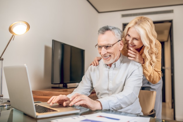 A couple. A man working from home, his wife standing next to him