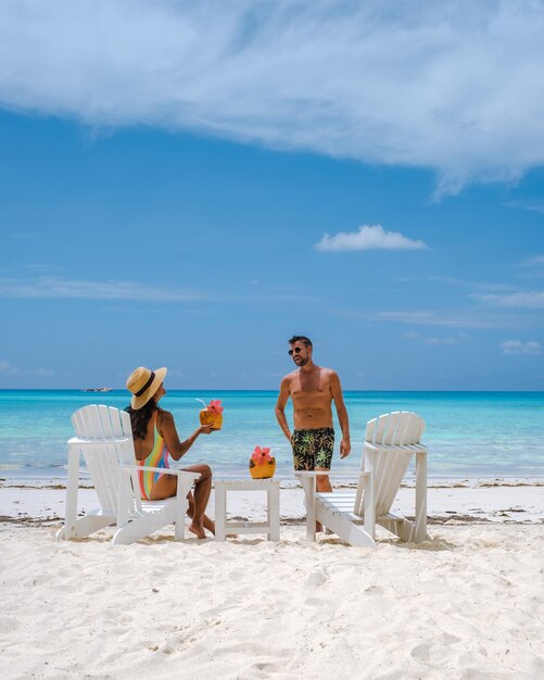 Couple men and women on the beach with coconut drink praslin seychelles tropical island with withe beaches and palm trees the beach of anse volbert seychelles