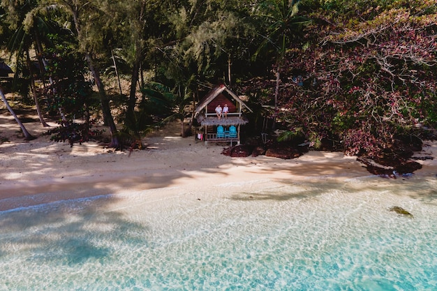 A couple of men and women relaxing on a white tropical beach with palm trees in Phuket Thailand