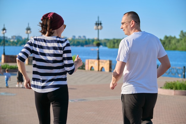 公園で走っている中年男性と女性のカップル。スポーツ、フィットネス、成熟した年齢の人々のアクティブな健康的なライフスタイル、背面図