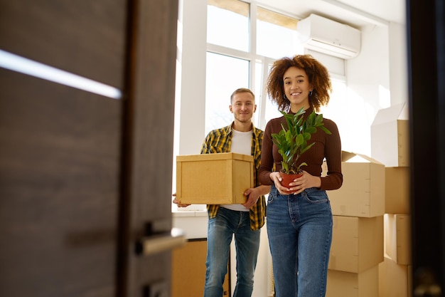 Couple on moving day carrying cardboard boxes