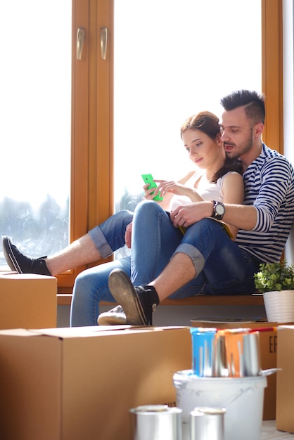 Photo couple moving in house sitting on the floor couple