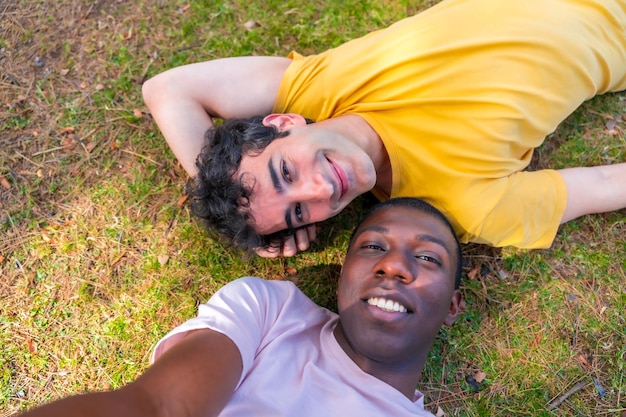 Selfieを取って草の上に横たわる公園lgbtコンセプトの多民族男性のカップル