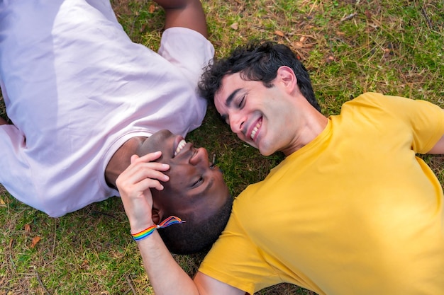 Couple of multiethnic men in a park lgbt concept lying on the grass