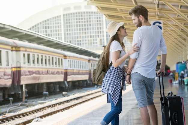 Photo couple of multiethnic travellers are looking together at the train station travel and lover concept