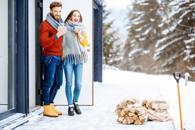 Couple near the house in the mountains during the winter