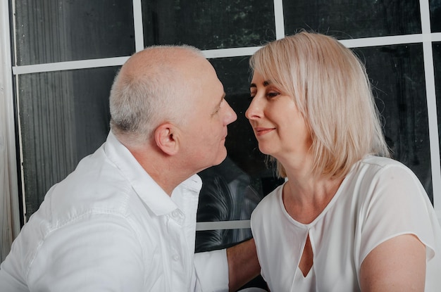 couple near the window hugging, kissing and smiling